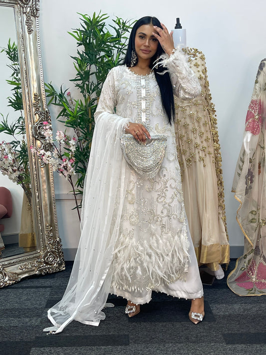 Woman in an embroidered traditional outfit standing in front of a mirror with floral decorations.