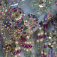 Close-up of decorative fabric with sequins, beads, and pearls on a gray background