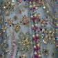 Close-up of decorative fabric with sequins, beads, and flowers on a light blue background