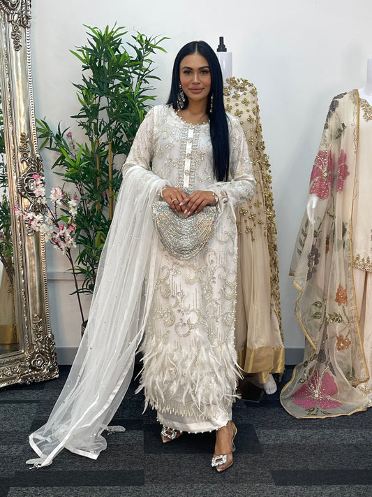 Woman in an embroidered traditional outfit standing in front of a mirror with floral decorations.