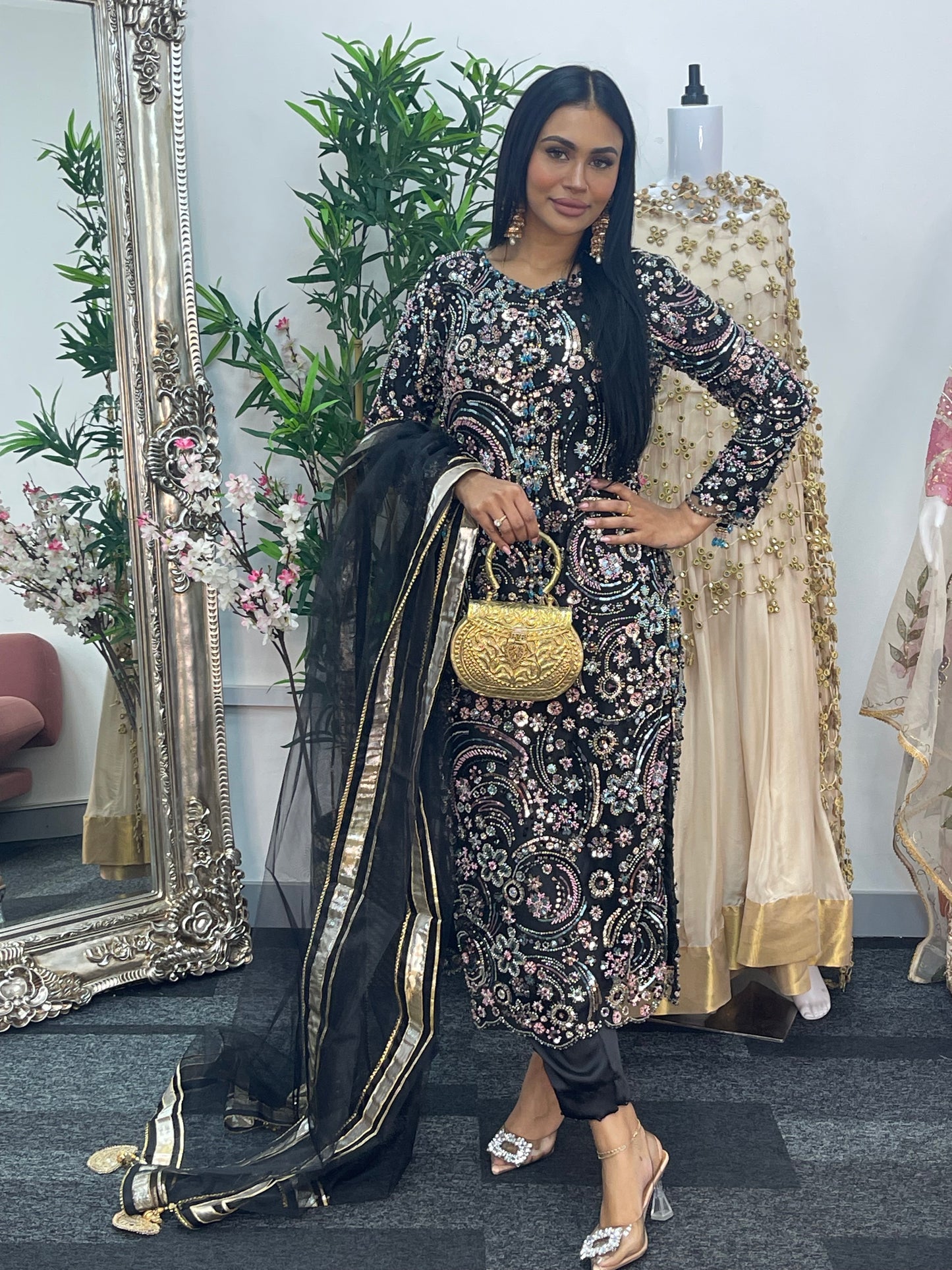 Woman in traditional outfit with floral patterns standing in front of a mirror.