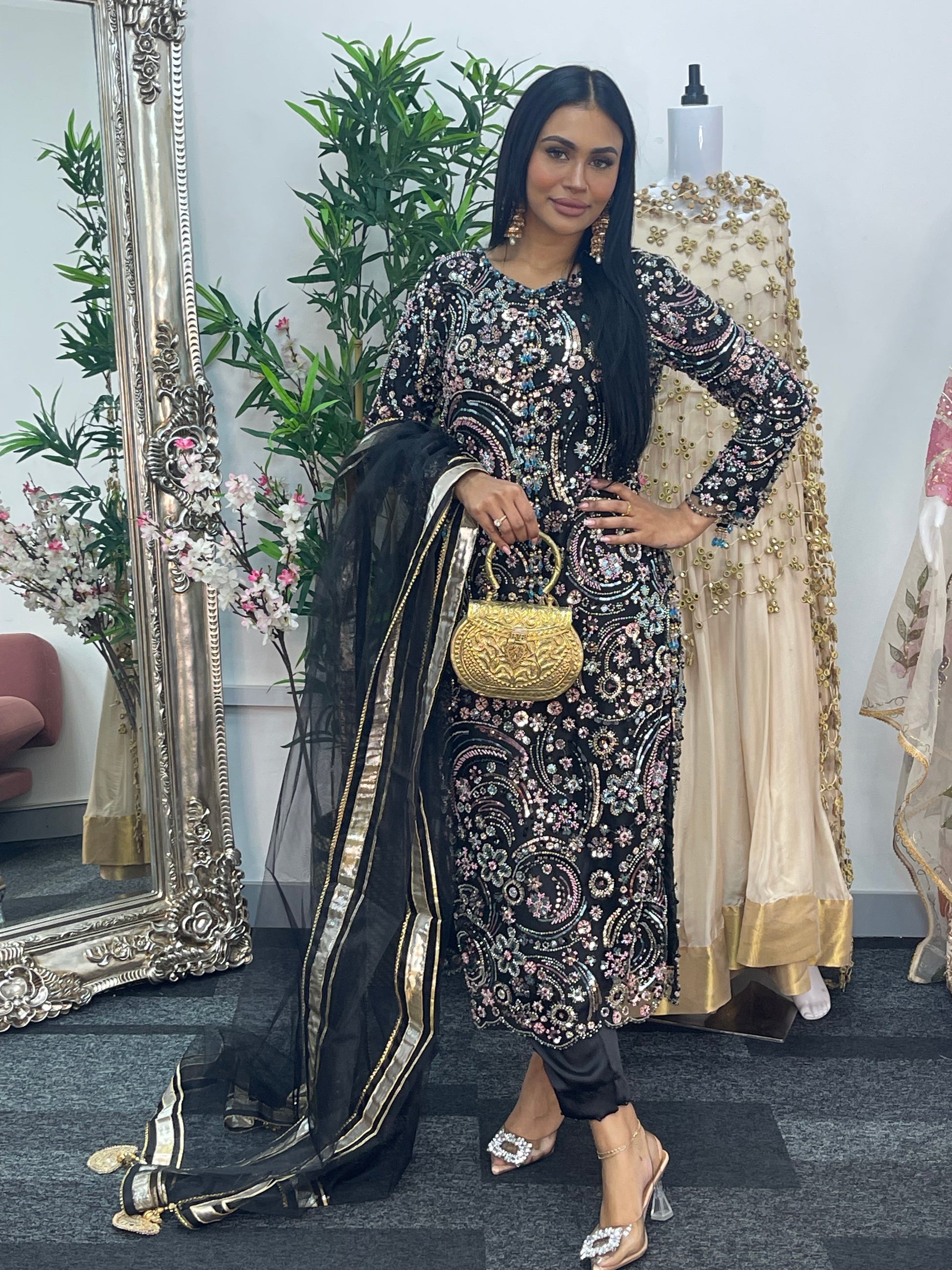 Woman in traditional outfit with floral patterns standing in front of a mirror.
